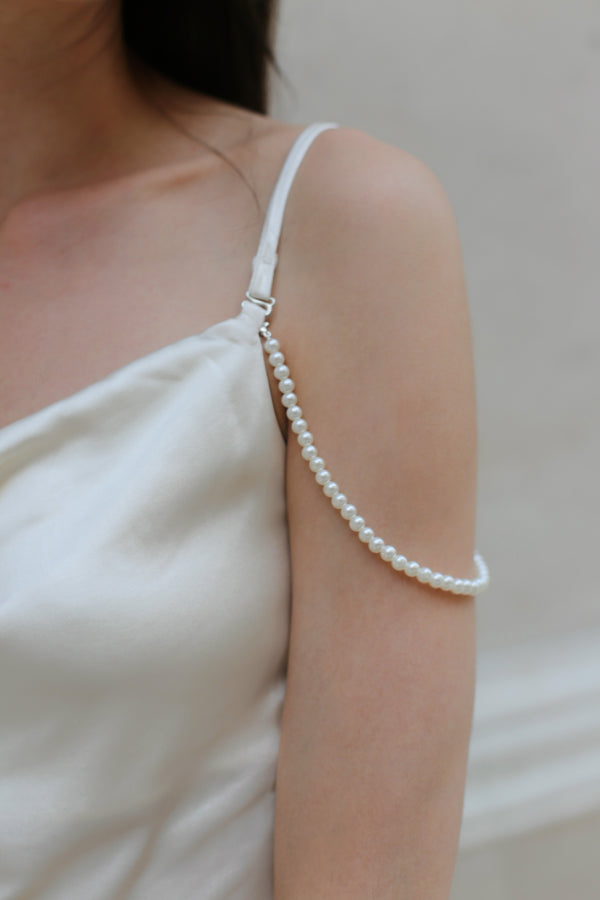 Close-up of pearl and feather details on ivory satin mini dress