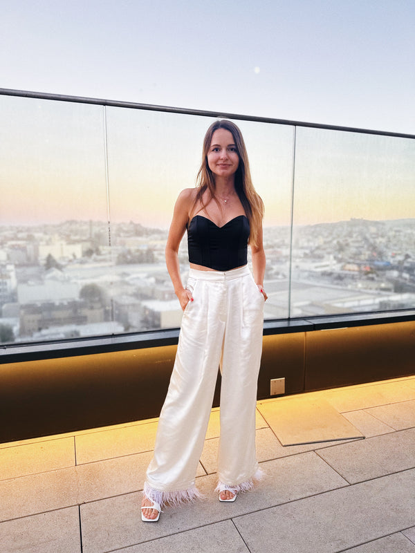 Model walking in ivory satin pants, capturing movement and shine
