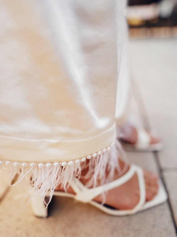 Close-up of ivory satin fabric texture and waistband detail